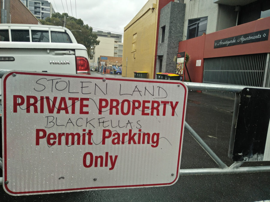 A sign reading 'PRIVATE PROPERTY / Permit Parking Only' is crossed out and rewritten as 'STOLEN LAND / BLACKFELLAS Only'